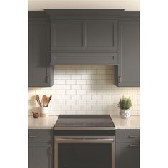 a stove top oven sitting inside of a kitchen next to gray cabinets and counter tops