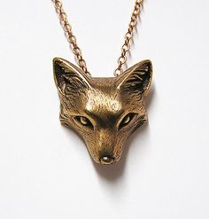 a gold necklace with a fox head on it