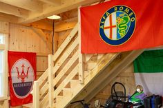 there are many flags hanging on the wall in this garage with bikes parked under it