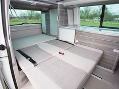 the interior of a camper van with mattresses and storage compartments on each side