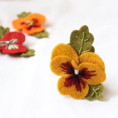 three felt flowers are sitting on a white surface