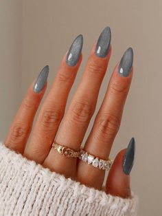 a woman's hand with grey and white nail polish on it, wearing a gold ring