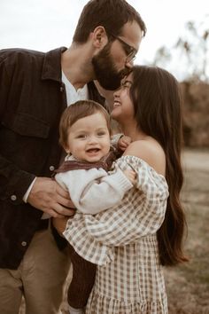 a man and woman holding a baby in their arms