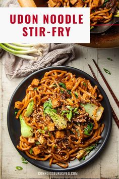 udon noodle stir - fry in a black plate with chopsticks on the side