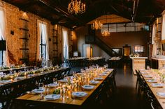 a long table set up with place settings and candles on it in a large room