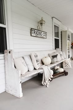 a white bench sitting on the side of a house next to a sign that says trading co