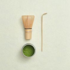 a wooden brush and green powder in a small bowl next to a bamboo toothbrush