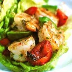 two lettuce wraps filled with shrimp and tomatoes on top of a white plate