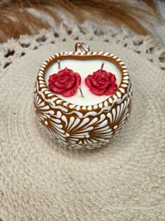 two red roses are placed on top of a white and brown box with intricate designs