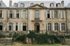 an old building with many windows and steps leading up to the front door on a cloudy day