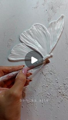 someone is painting a butterfly on the wall with white paint and watercolor pencils