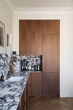 a kitchen with marble counter tops and wooden cabinets, along with wood flooring that matches the walls