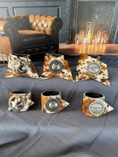 five pieces of pottery sitting on top of a gray cloth covered table next to a couch