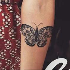 a woman's arm with a black and white butterfly tattoo on the left forearm