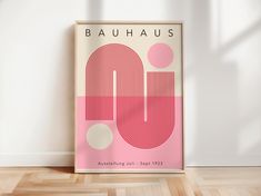 a pink poster with the word bauhaus on it in front of a white wall