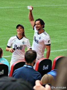 two soccer players are holding their hands up in the air as they walk off the field