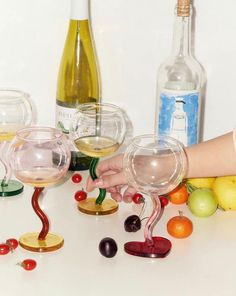 two wine glasses with cherries on the rims, one being held by a person's hand