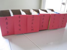 four pink books with writing on them sitting on top of a white table in front of a window