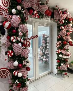 christmas decorations are hanging on the wall in front of an open door with candy canes and