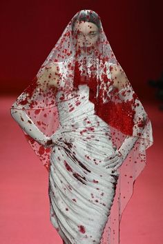 a white dress with red splatters on it and a veil over its head