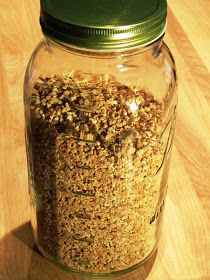 a glass jar filled with granola sitting on top of a wooden table next to a green lid