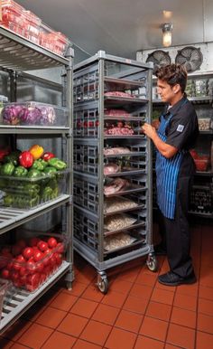 a man standing in front of an open refrigerator filled with lots of vegetables and fruits