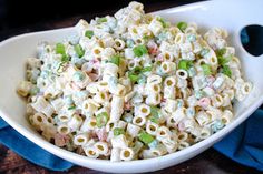 a white bowl filled with macaroni salad on top of a wooden table next to a blue towel