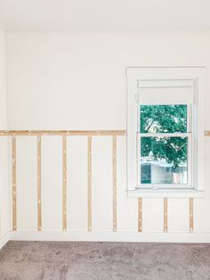 an empty room with white walls and wood framing on the wall is being renovated by someone