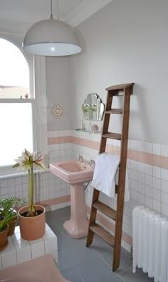 a bathroom with a pink sink and wooden ladder