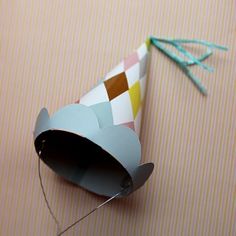 a party hat made out of paper on top of a pink surface with a string attached to it