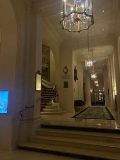 a chandelier hanging from the ceiling in a large room with white walls and stairs