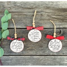 three christmas ornaments hanging on a wooden surface with greenery around them and the names of each ornament