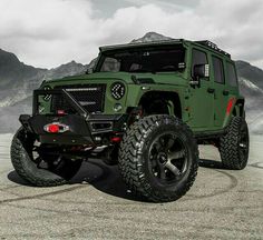 a green jeep parked on top of a sandy beach