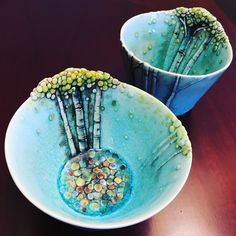 two blue bowls with trees painted on them