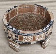 an old wooden bowl sitting on top of a table next to a brown and white wall