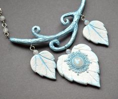 the necklace is decorated with blue and white leaves, beads, and a pearl bead