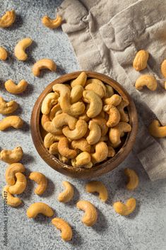 a wooden bowl filled with cashews on top of a table