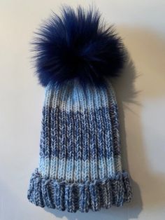 Cute and fashionable knitted hat made with the softest yarn in a warm thick-stitch knit. Acrylic/alpaca/wool/viscose. Topped with a large blue faux-fur pompom. Blue Knit Beanie For Winter, Blue Wool Knitted Beanie, Blue One Size Knit Beanie, Blue One-size Knit Beanie, Blue Winter Beanie, Blue Knit Winter Hat, Blue Knit Beanie Hat, Blue Wool Beanie, Knitted Blue Beanie For Fall