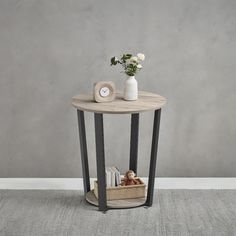 a small round table with a basket on the bottom and some flowers in front of it