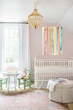 a baby's room with pink walls and white furniture