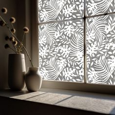 two vases sitting on a window sill with flowers in front of the blinds