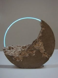 an object made out of concrete with a neon ring around it's center, sitting on a white surface