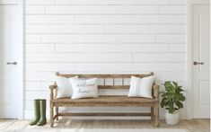 a wooden bench sitting in front of a white brick wall with two green boots on it