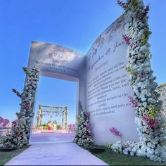 an archway decorated with white flowers and greenery