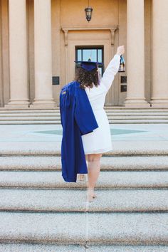 a woman in a graduation cap and gown is walking up the steps with her arms raised