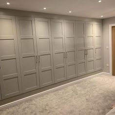 an empty room with white cabinets and carpeted flooring in front of the doors