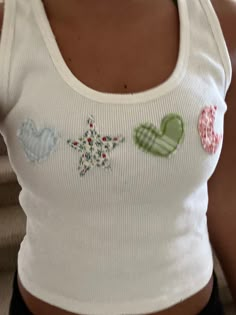 a close up of a person wearing a white tank top with hearts and snowflakes on it