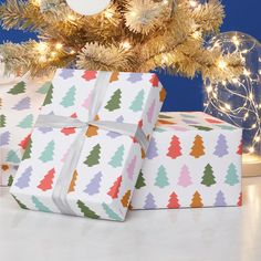 two wrapped presents under a christmas tree with lights on the branches in front of it