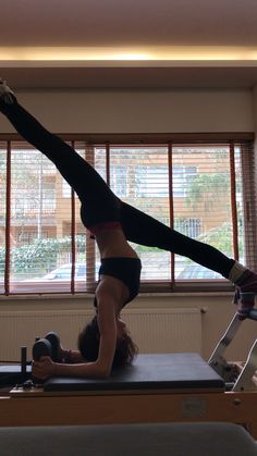 a woman is doing exercises on a piyom machine in front of a window