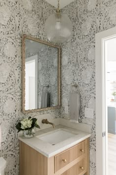 a bathroom with a mirror, sink and wall papered in floral designs on the walls